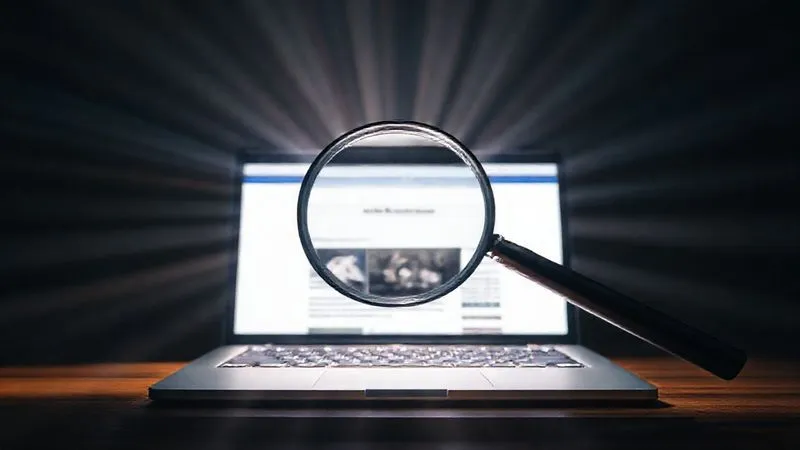 Photorealistic image of a magnifying glass over a laptop screen displaying a blog post, with light rays expanding outwards, cinematic lighting.