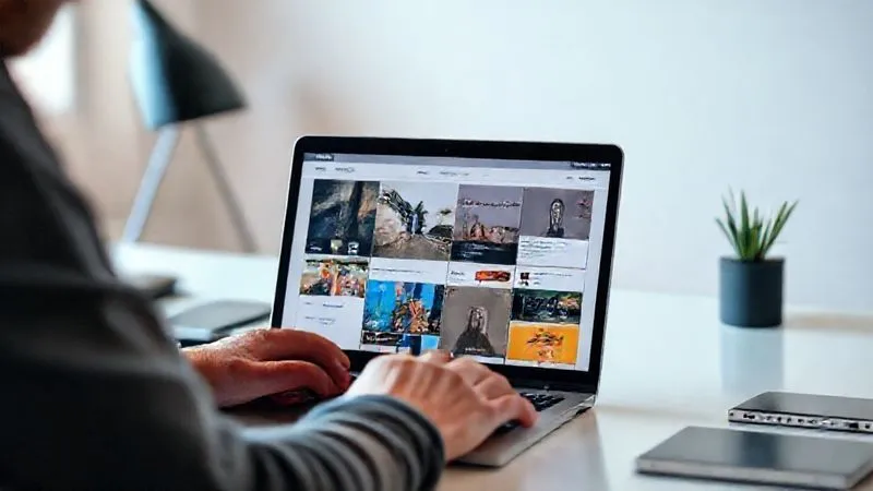 Photorealistic image of a digital nomad meticulously curating an online portfolio on a sleek laptop, showcasing various projects (e.g., website designs, marketing campaigns, code snippets). The background is a clean, minimalist workspace. Cinematic lighting, sharp focus on the portfolio details, depth of field blurring the background. 8K hyper-detailed, professional photography, shot on a high-end DSLR.