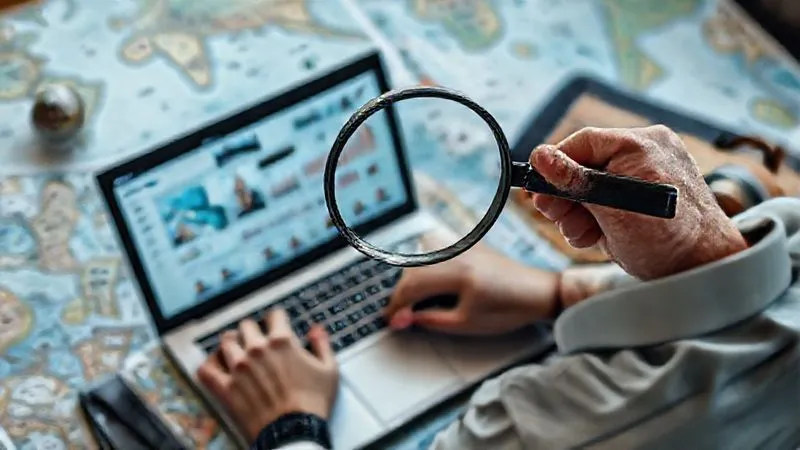 A photorealistic image of a person meticulously sifting through social media profiles on a laptop, with a magnifying glass over a screen showing influencer metrics and demographics, surrounded by maps and travel-related items. Professional photography, 8K, cinematic lighting, sharp focus on the laptop screen, depth of field blurring the background, shot on a high-end DSLR, thoughtful and analytical mood.